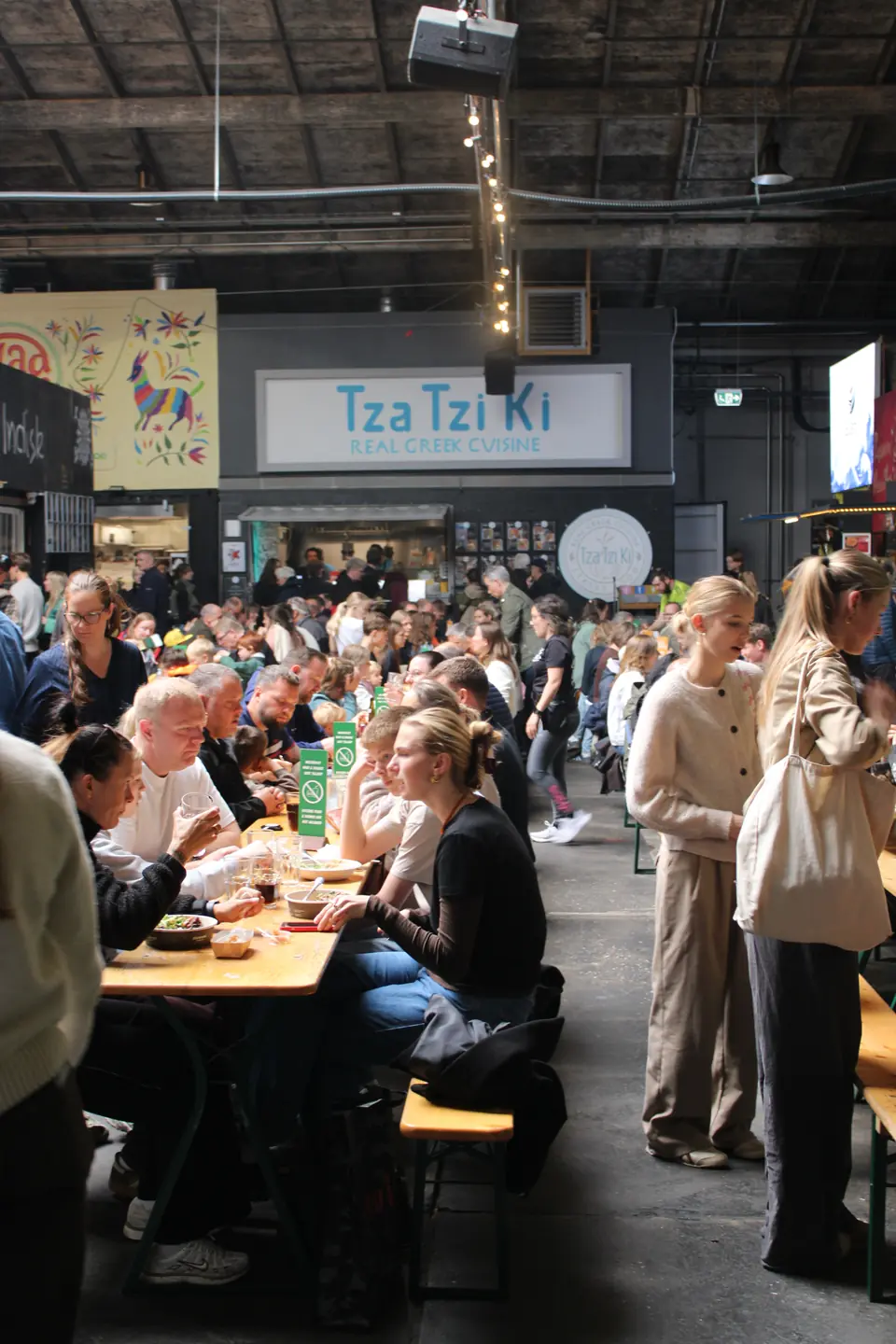 Gäste an langen Tischen in der Garagen vor Tza Tzi Ki